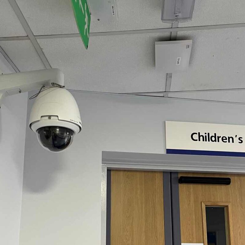 ngineer installing a protective CCTV camera cover to help prevent CCTV camera damage in a public building